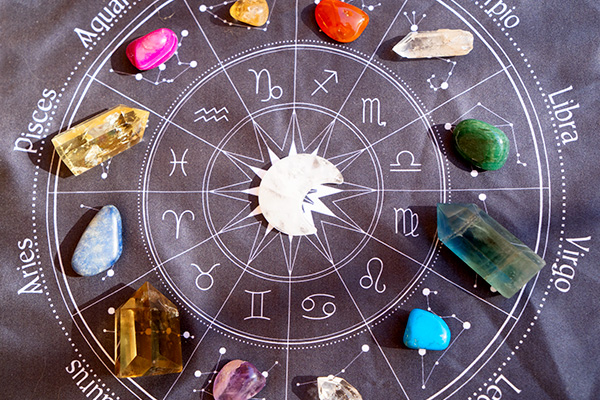 Mehrere Geburtssteine liegen auf einem aufgemalten Kreis-Horoskop