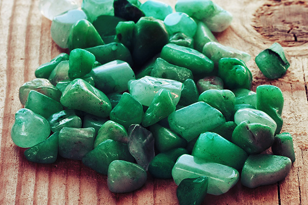 Mehrere Jade-Steine in unterschiedlichen Grüntönen und Größen auf Holz