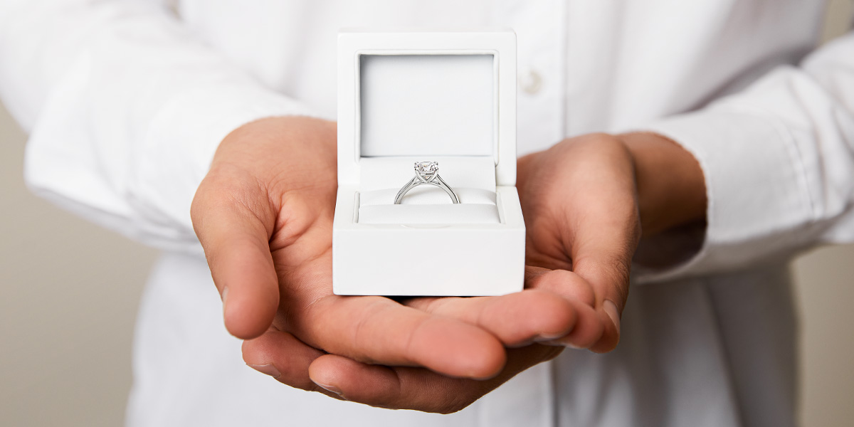 Een man houdt een verlovingsring in een doosje