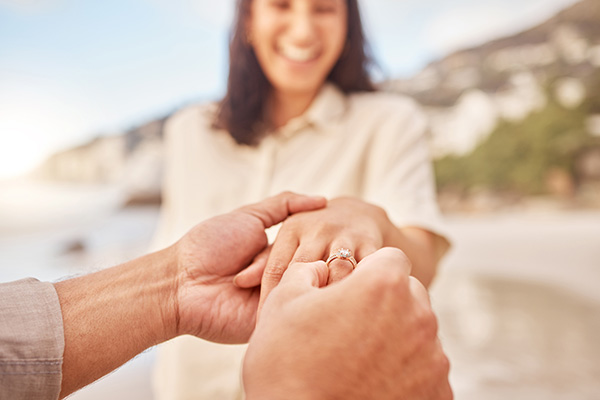 Man placing an engagement ring on his girlfriend's left finger